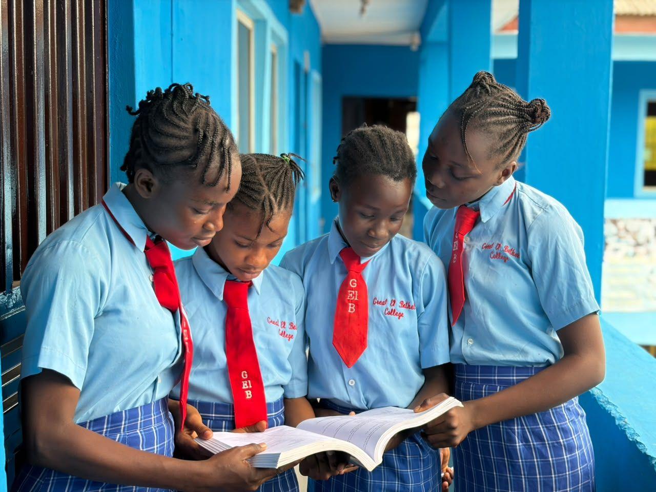 Four students reading together on the school corridor